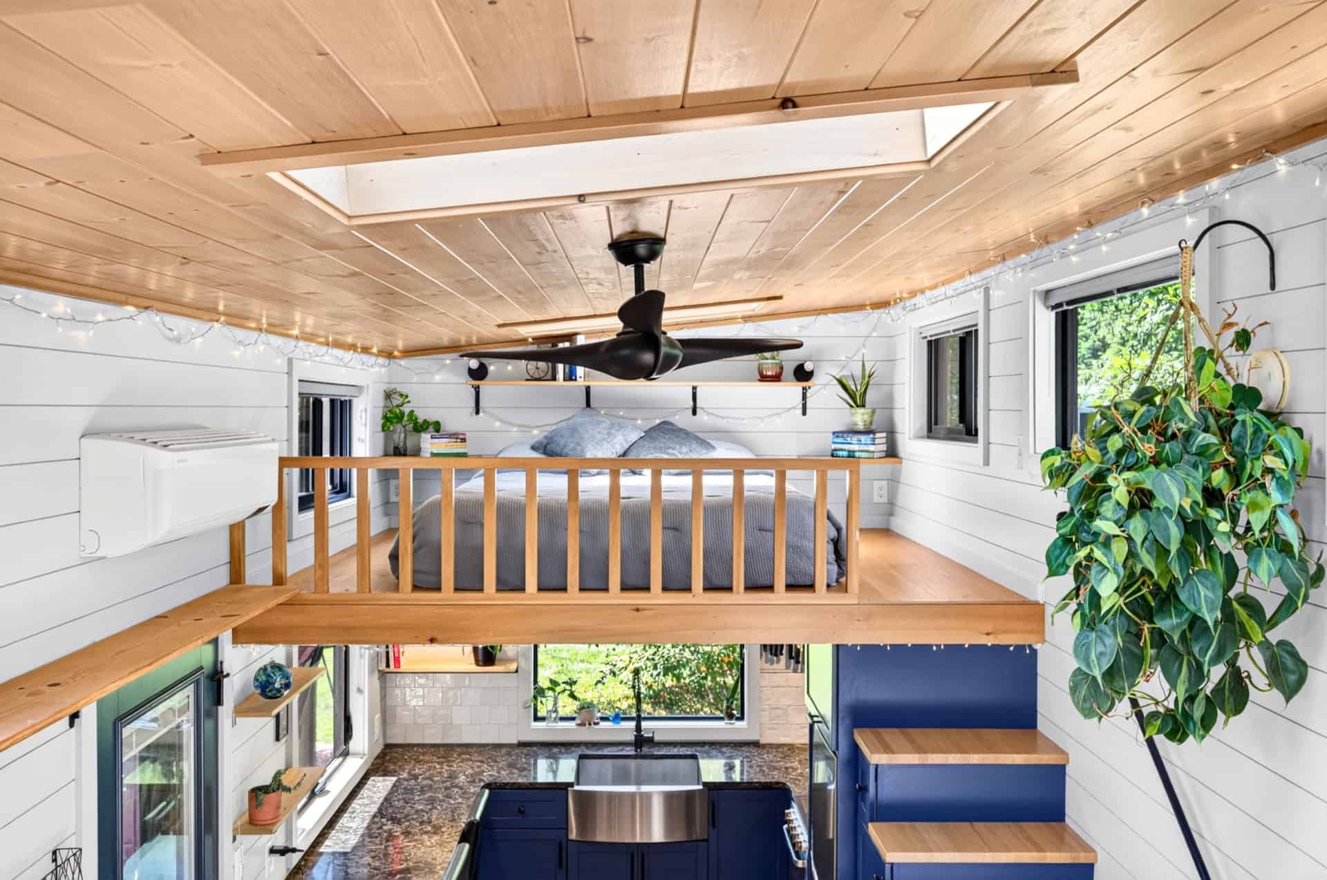 View from the loft down over the kitchen and living area with ceiling fan and skylights