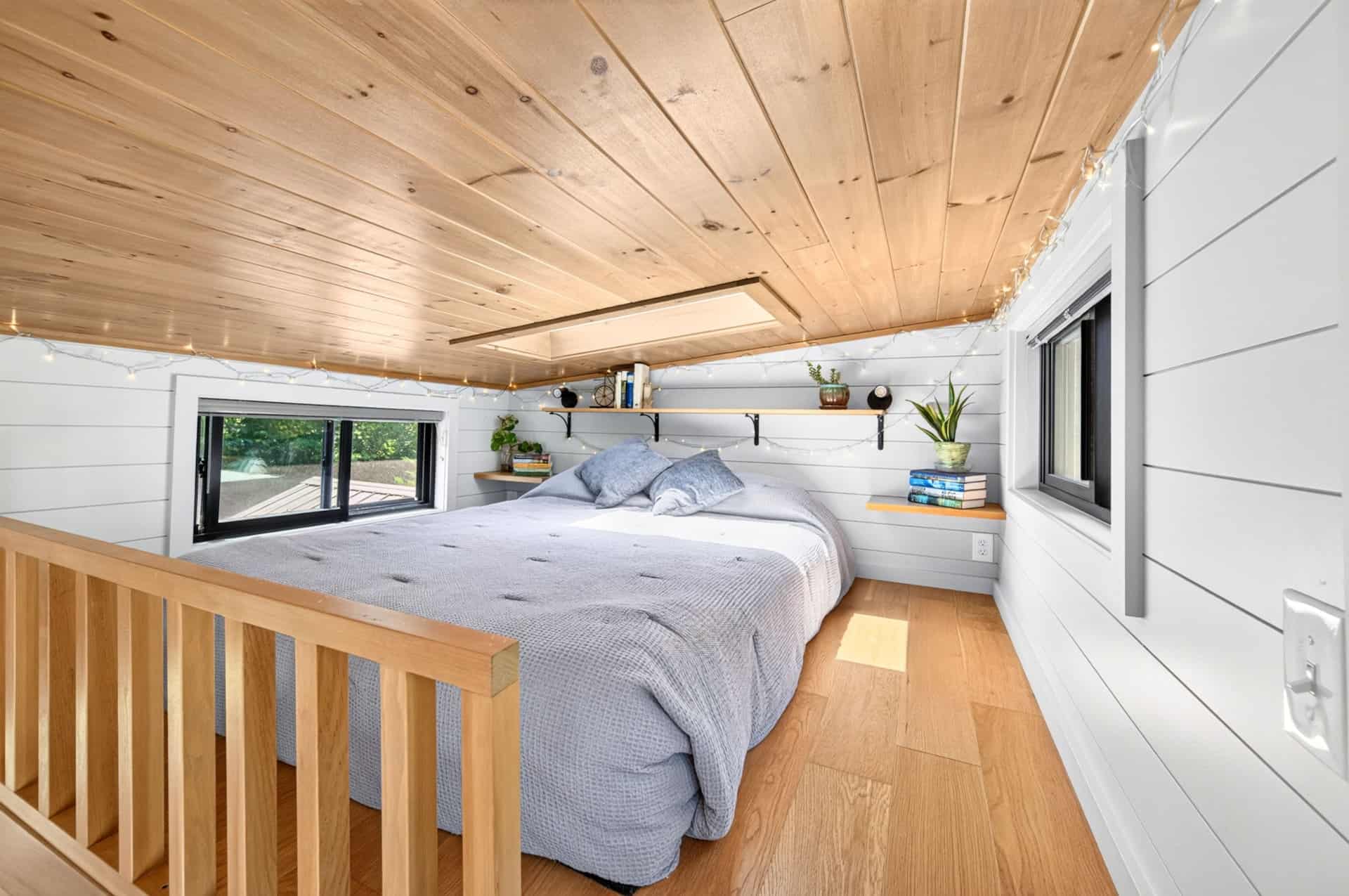 Primary sleeping loft with wood ceiling, skylight, and shelf ledges