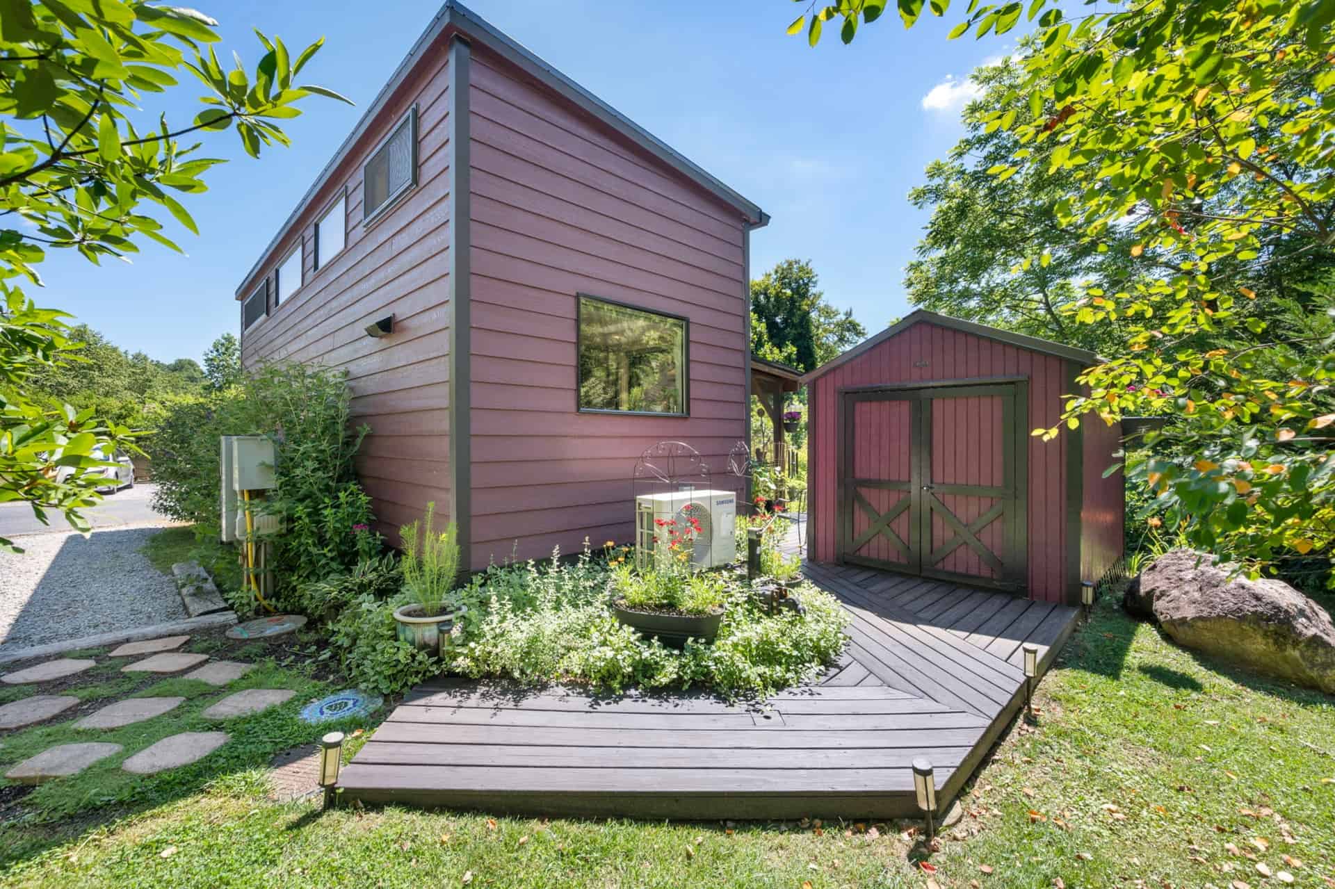 Matching storage shed and heat pump beside the tiny house on a wooden boardwalk