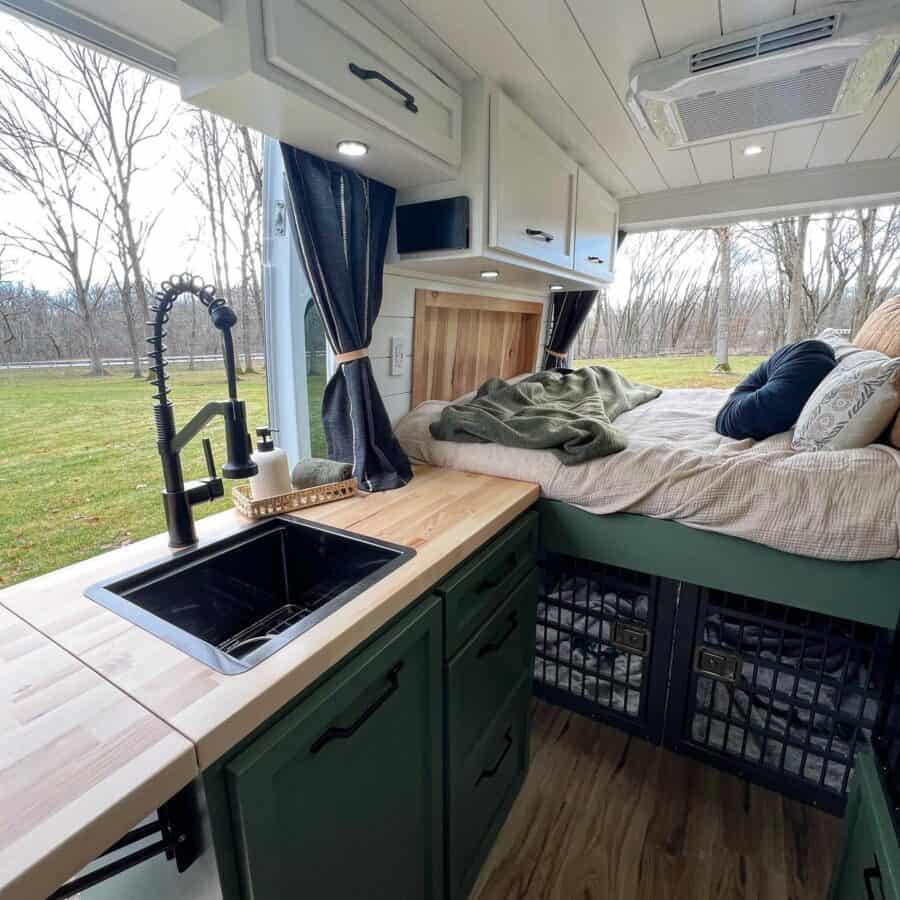 Cozy tiny house interior featuring a bed and double dog crates underneath.