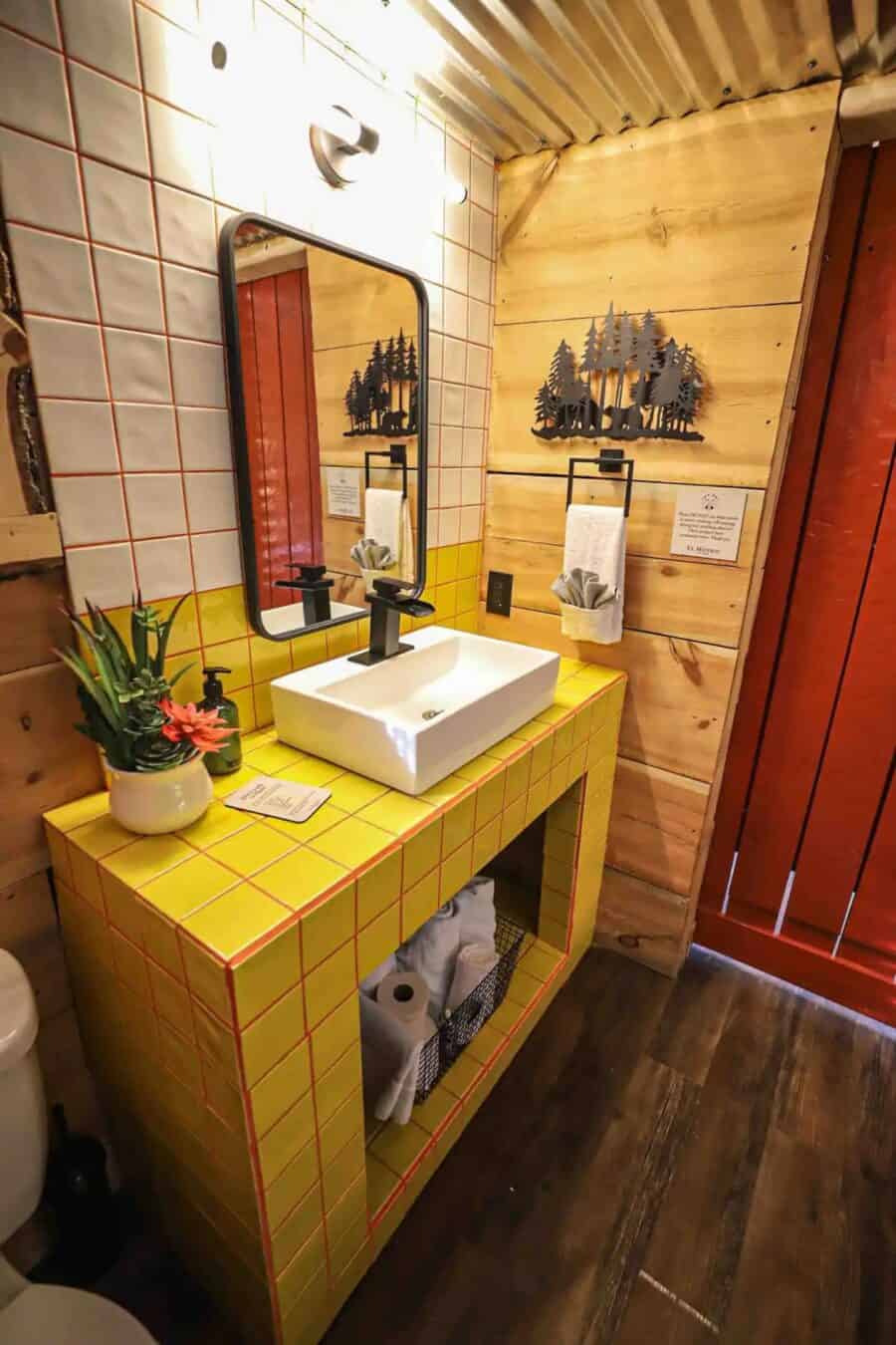 Bathroom sink with yellow tiled vanity and black fixtures.