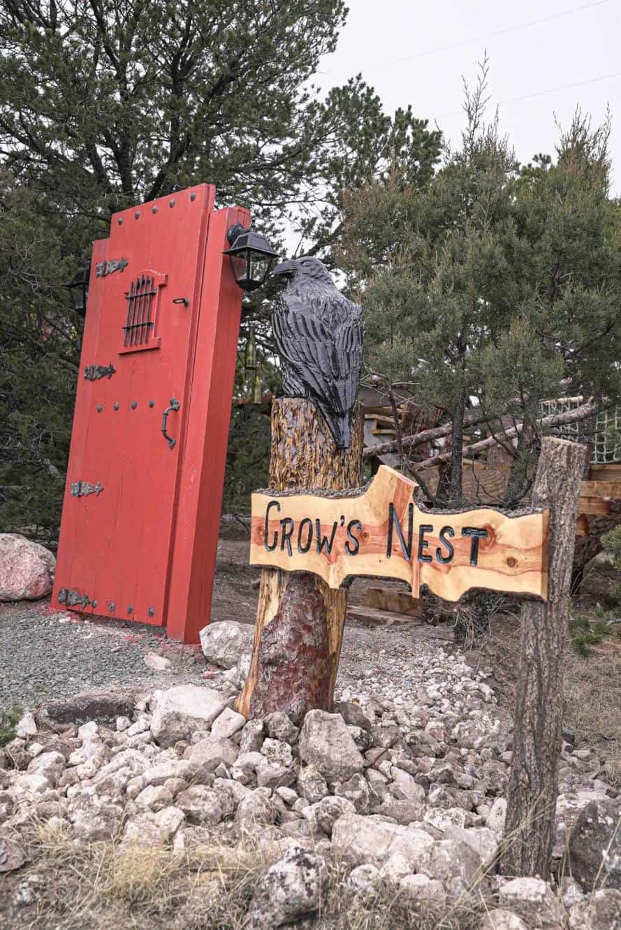 Charming treehouse named Crow's Nest featuring a twisty slide and rustic decor. Perfect for outdoor.