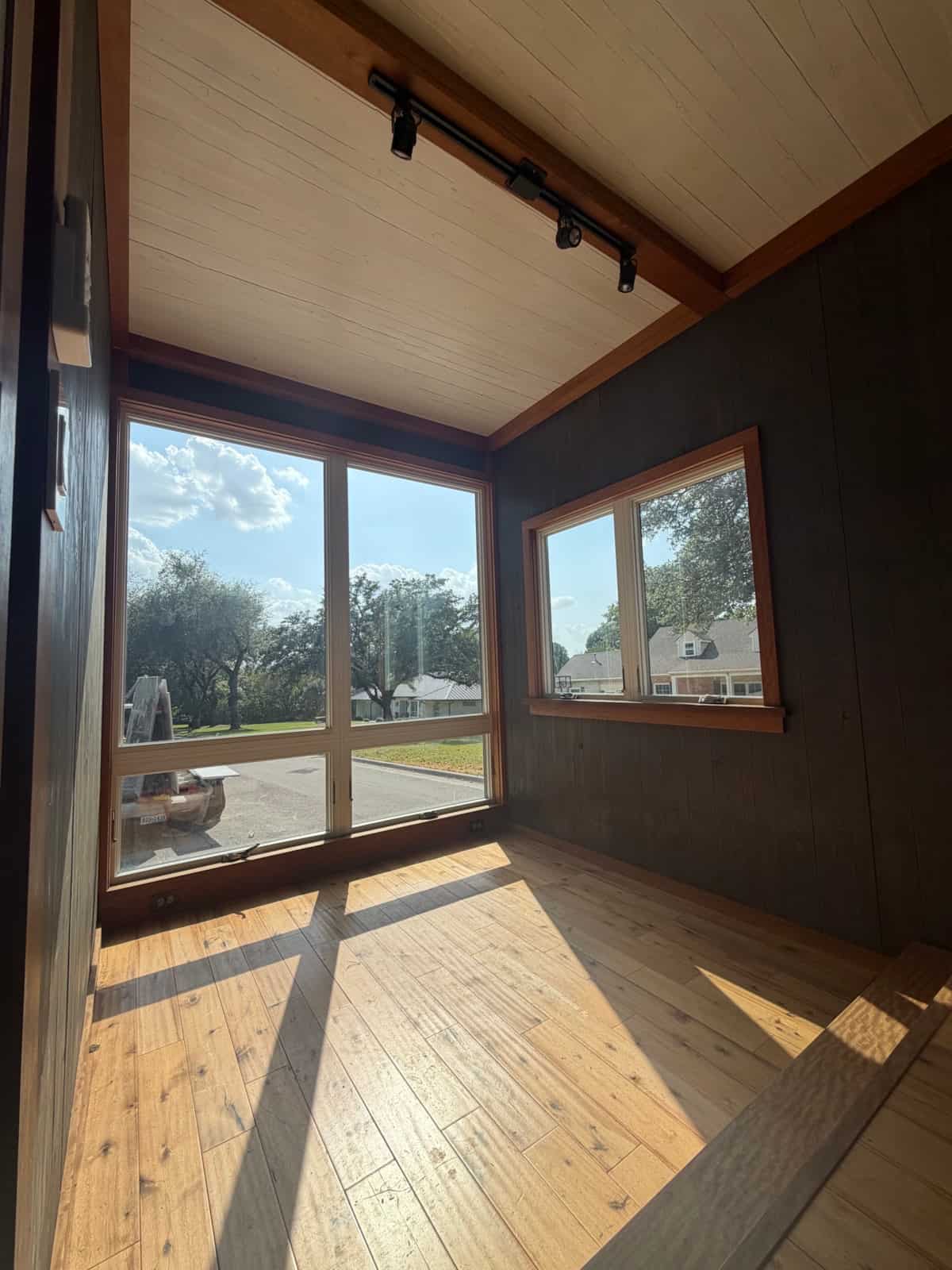 Current interior of the Adirondack tiny house for sale showing wood floors, dark walls and the raised floor platform