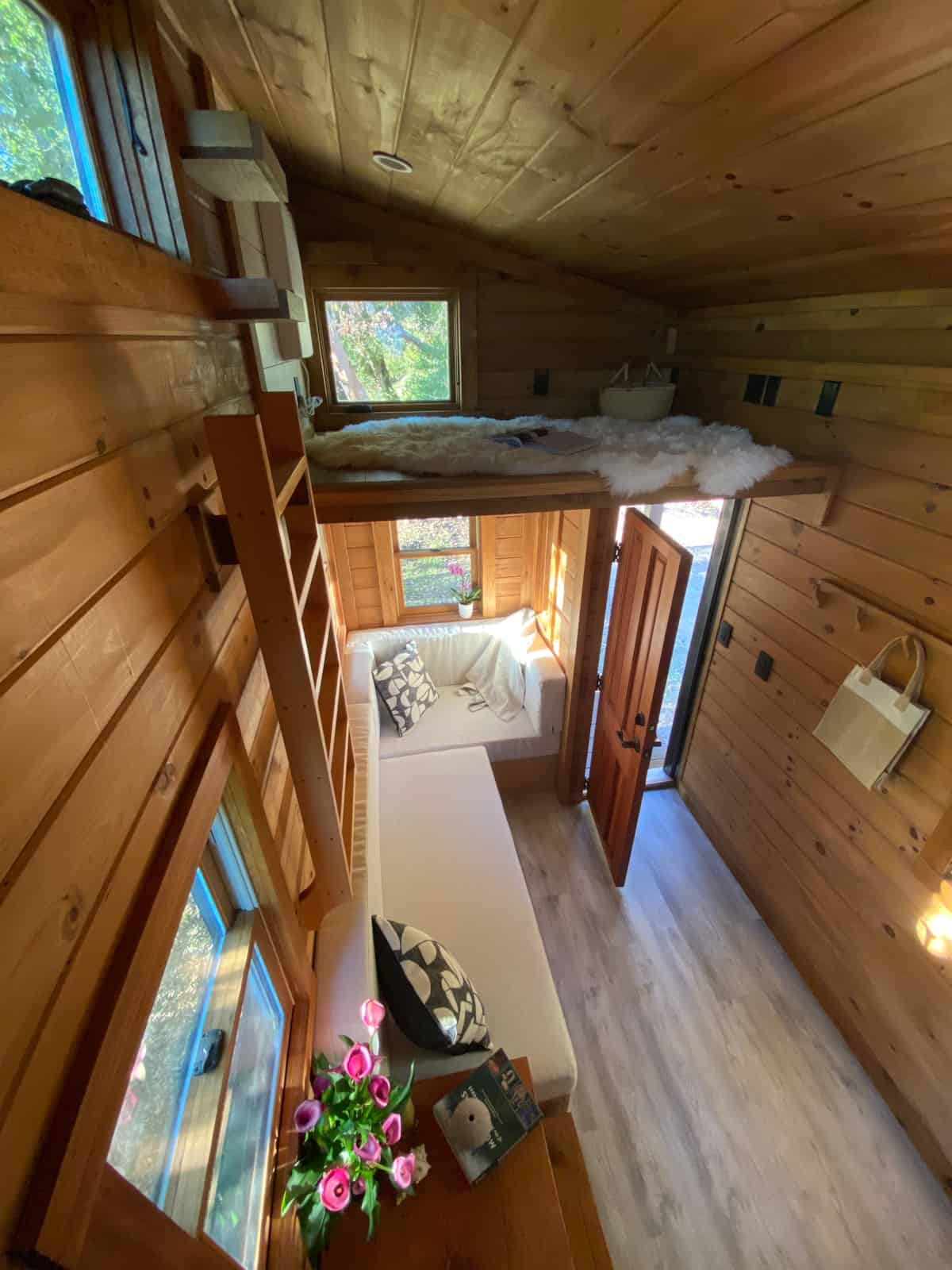 View from the loft down into the living area showing the ladder, sofa and front door