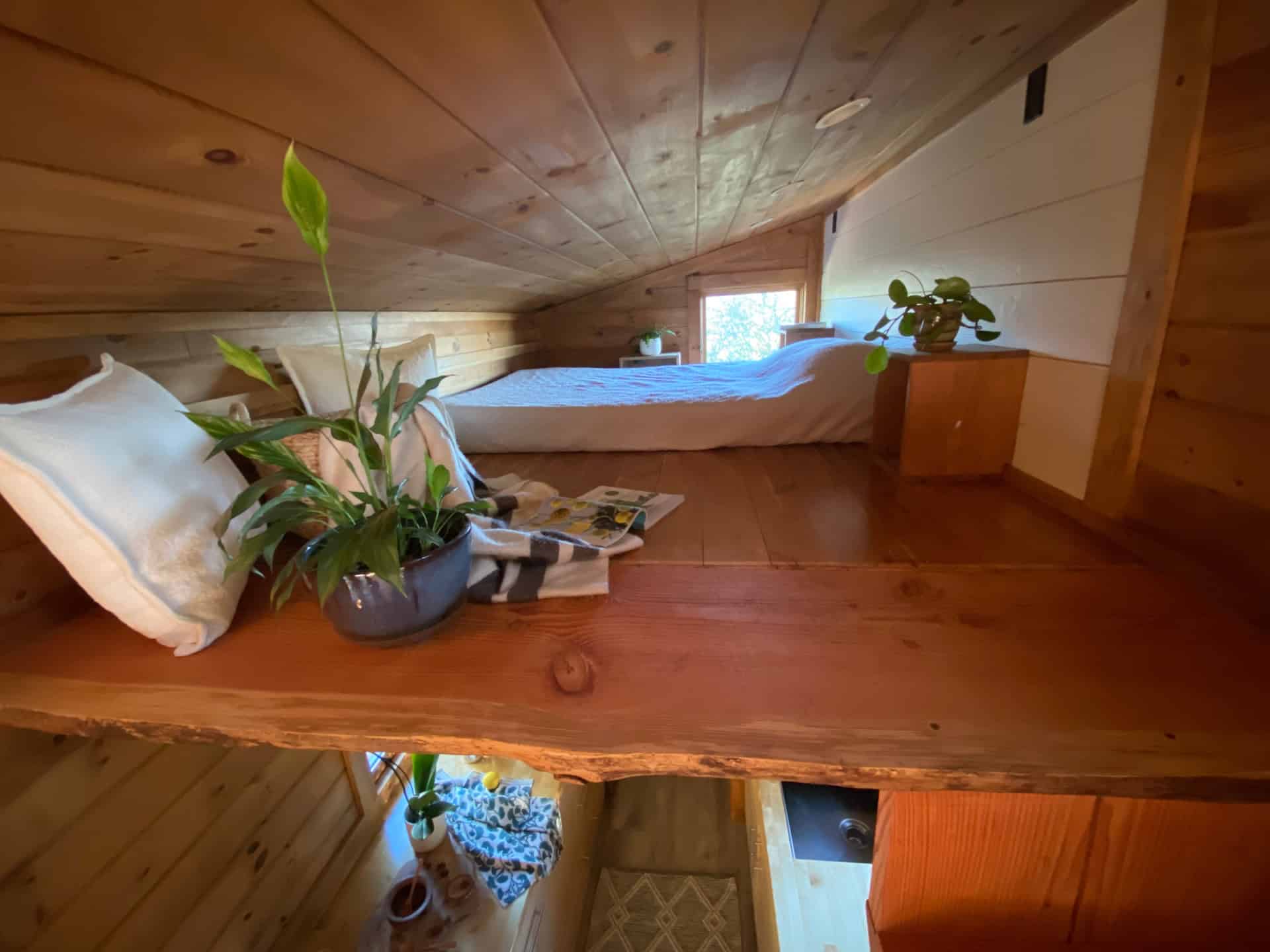 Master sleeping loft with bed, built-in nightstand and live-edge timber beam