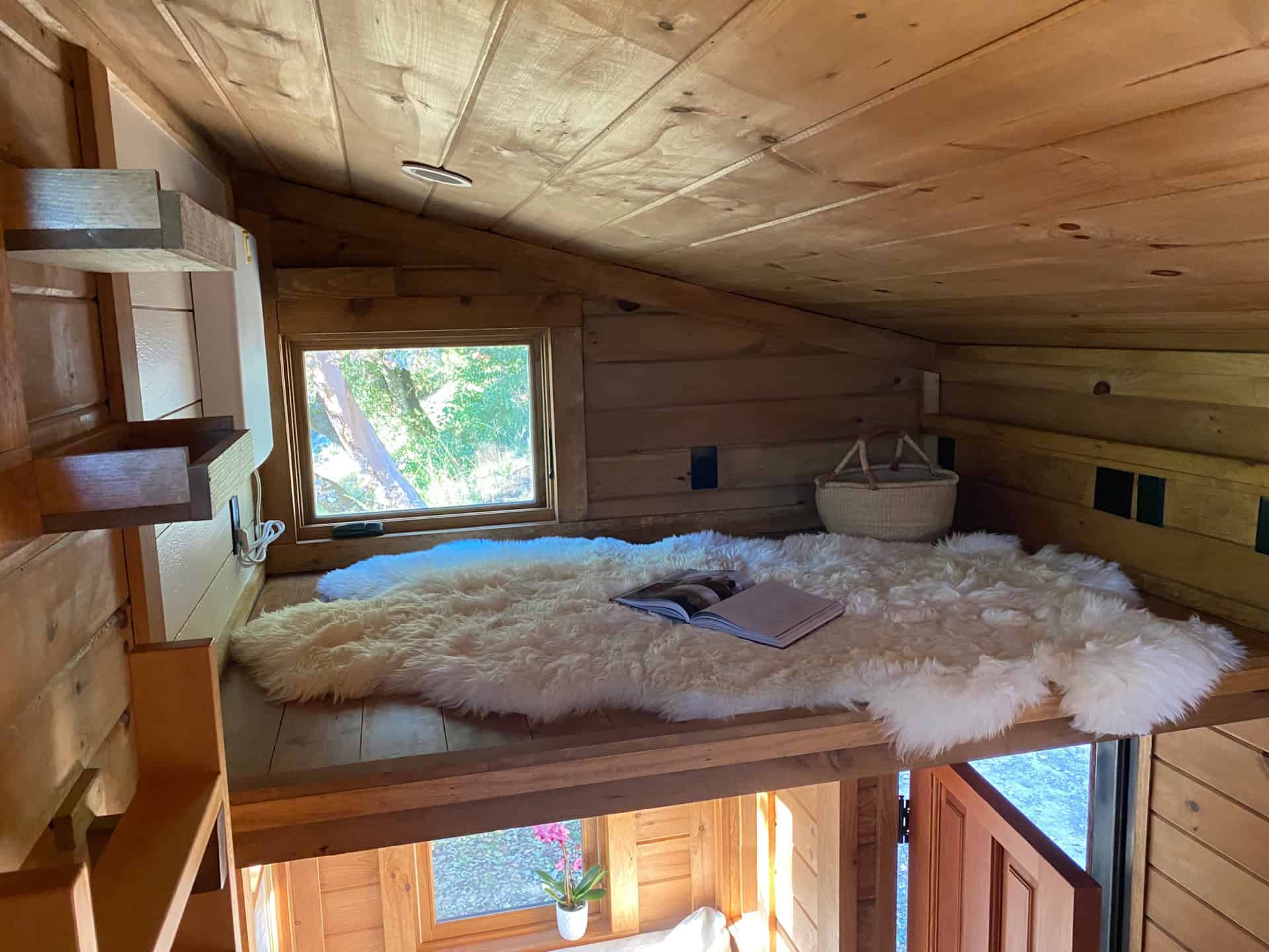 Second loft above the living area with window, sheepskins and exposed wood ceiling
