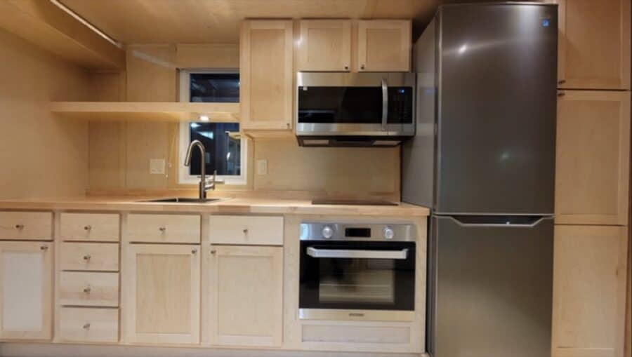 Modern tiny house kitchen featuring upgraded entertainment center and sleek appliances.