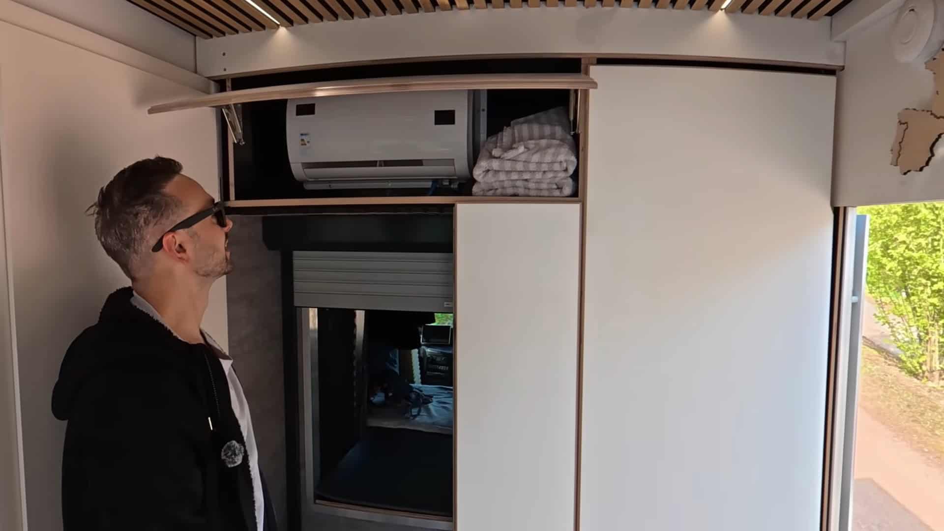 Air conditioning unit and storage cabinet hidden behind lift-up panel in the truck camper