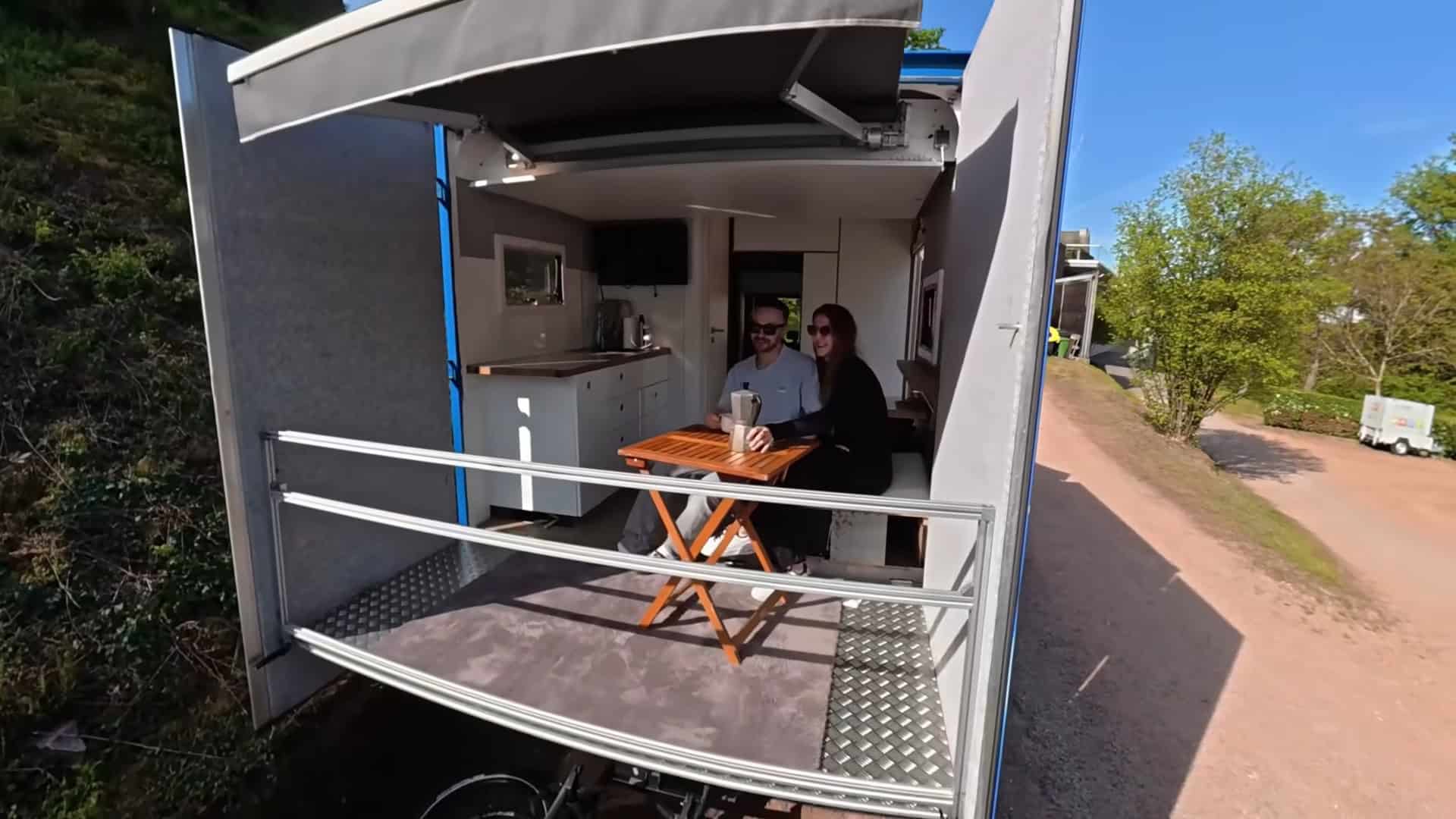 Couple enjoying morning coffee on the sky balcony of their DIY semi-truck tiny home