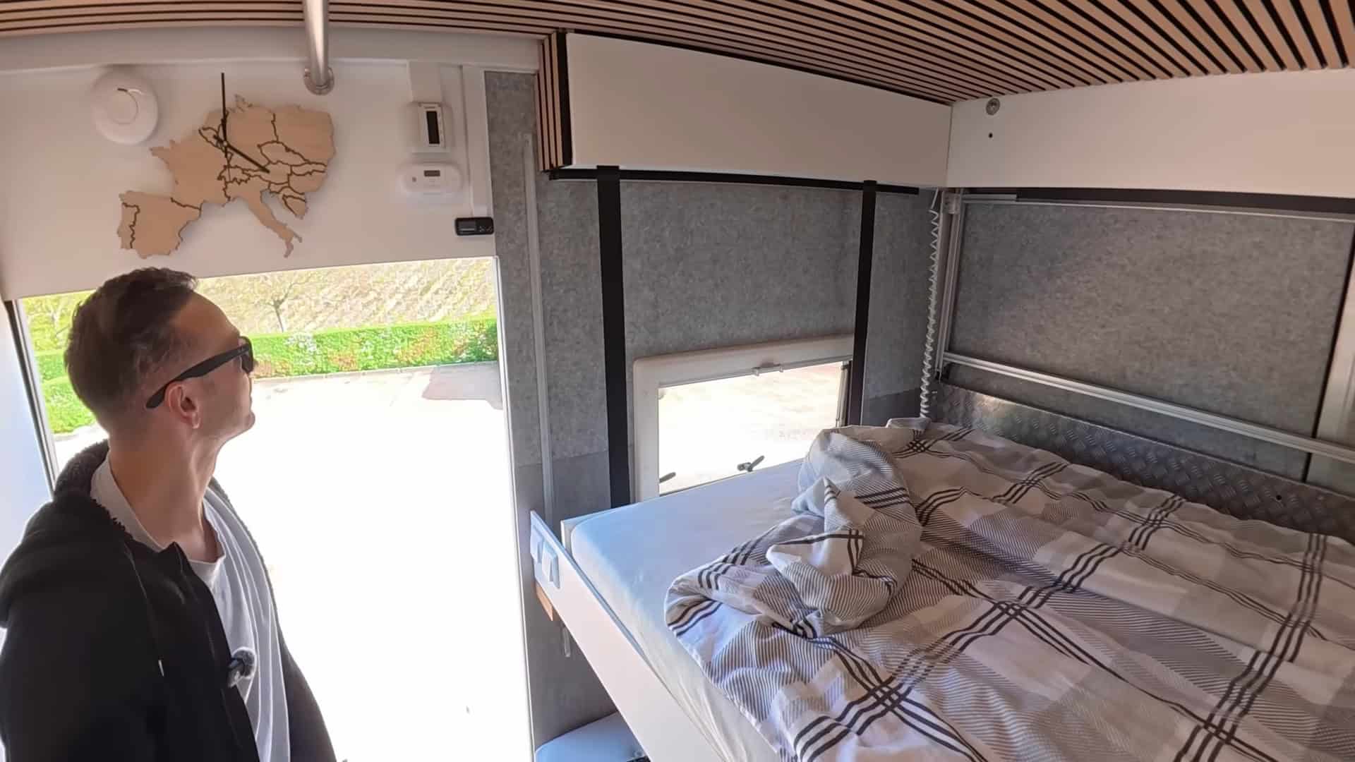 Drop-down elevator bed fully lowered showing the wood-slatted ceiling and diamond-plate accent wall