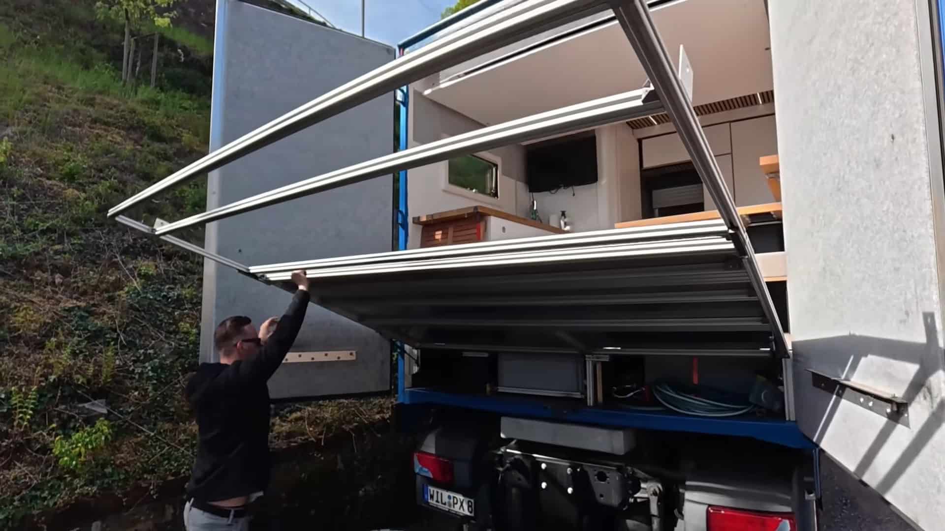 Waldemar deploying the fold-down sky balcony mechanism on the rear of the semi-truck camper