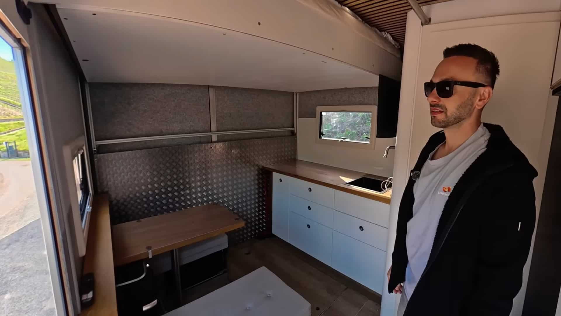 Interior of the truck tiny house with balcony door open showing mountain countryside views