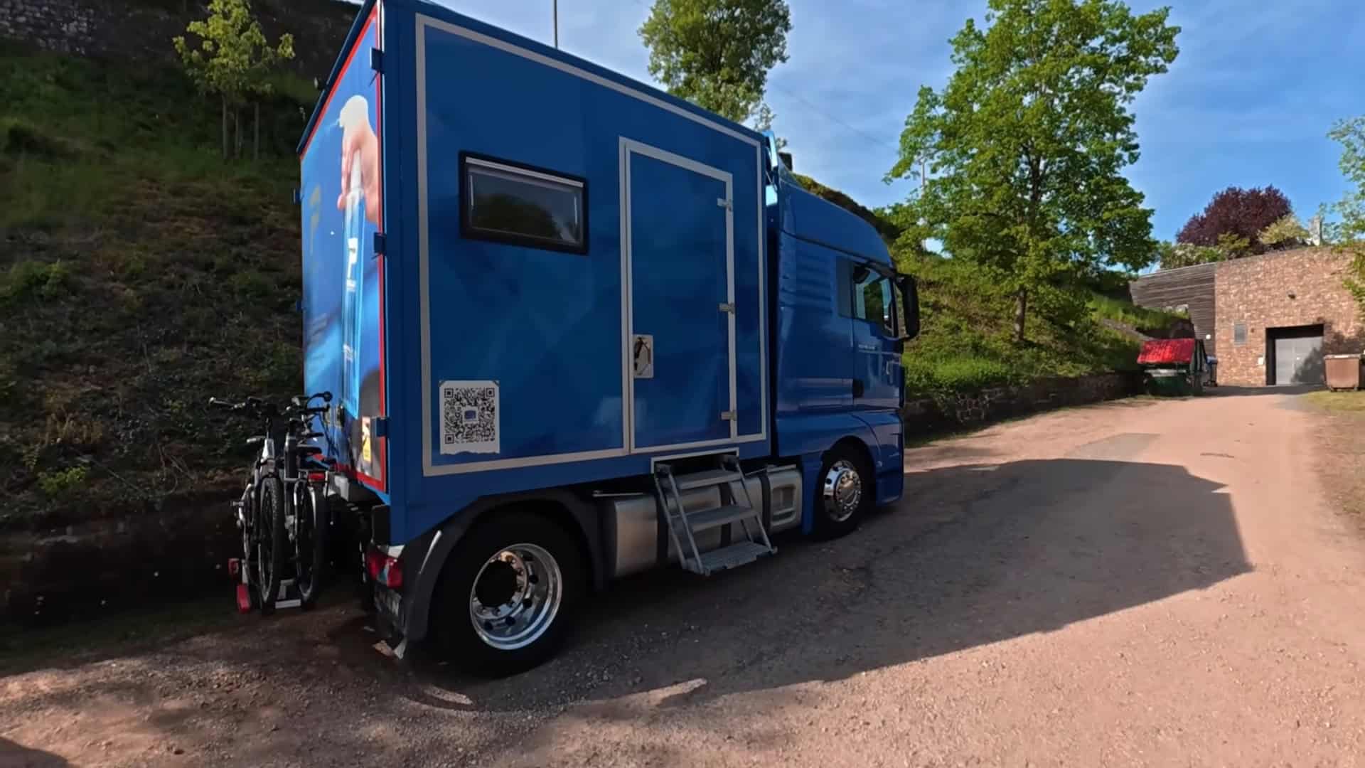 Rear view of the DIY semi-truck tiny house showing custom cargo box, bike rack, and MAN truck badge