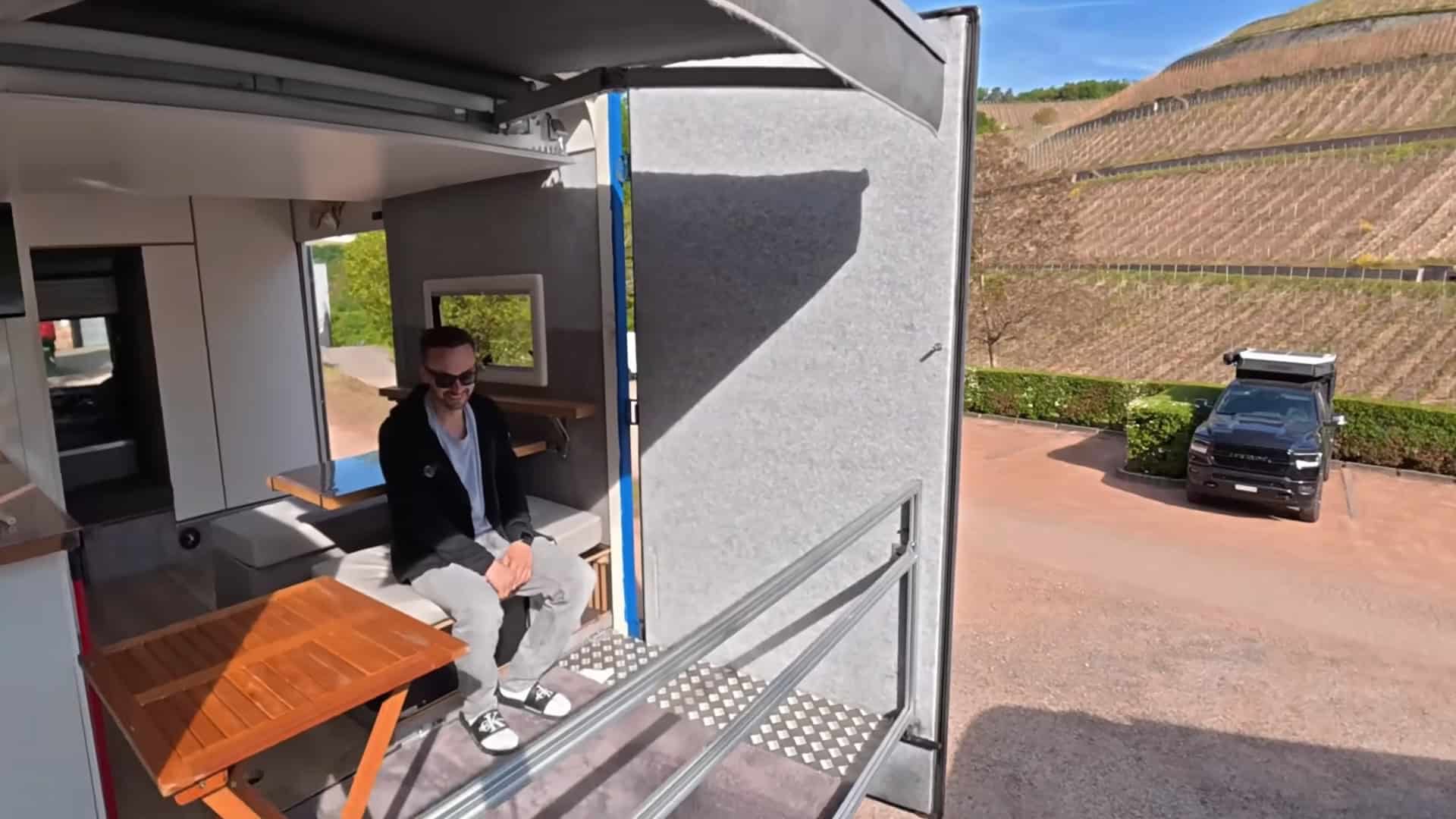 Waldemar sitting on the elevated sky balcony overlooking a vineyard and hillside campsite