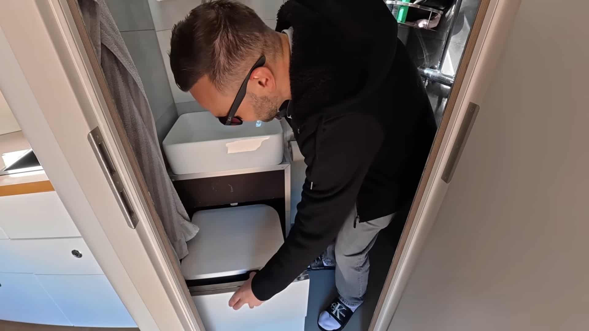 Waldemar demonstrating the hidden slide-out toilet tucked under the cabinetry