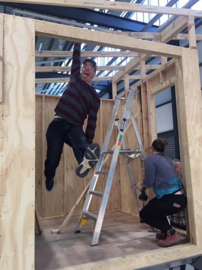 Two people building the wooden frame of a tiny house during Deek's Tiny House Summer Camp.