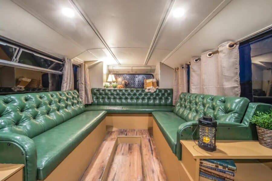 Cozy family bus converted into a small coffee shop and Airbnb with green leather seating.