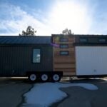Modern tiny house on wheels with sleek black and white exterior, built for mobility and small space.