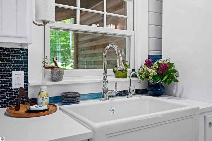 Bright kitchen featuring a large window, white cabinetry, and stylish faucet in a tiny home.