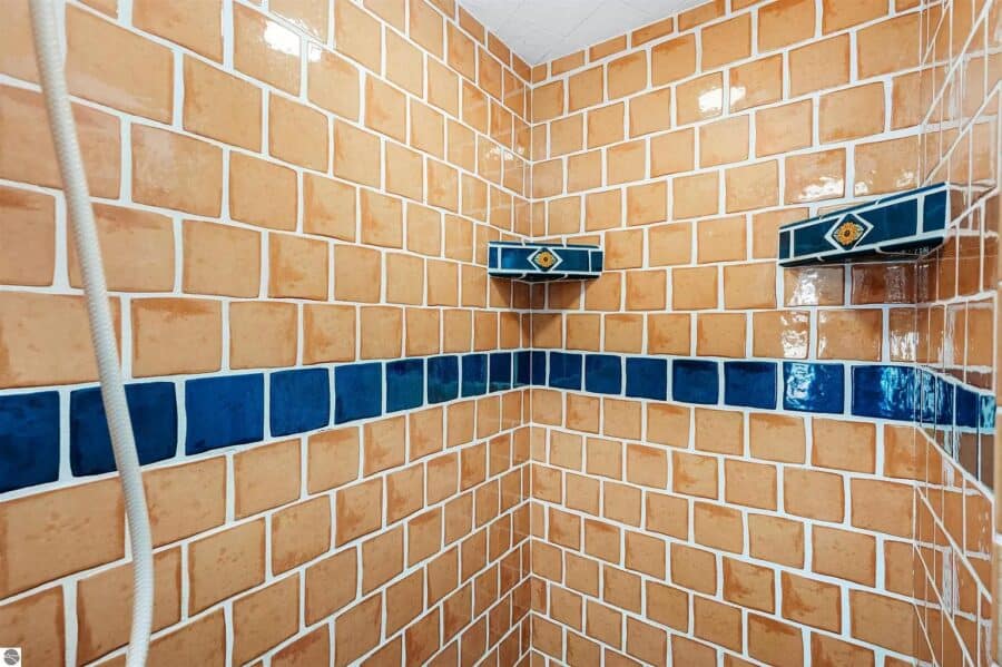 Bright orange and blue tiled shower wall in a tiny house bathroom.