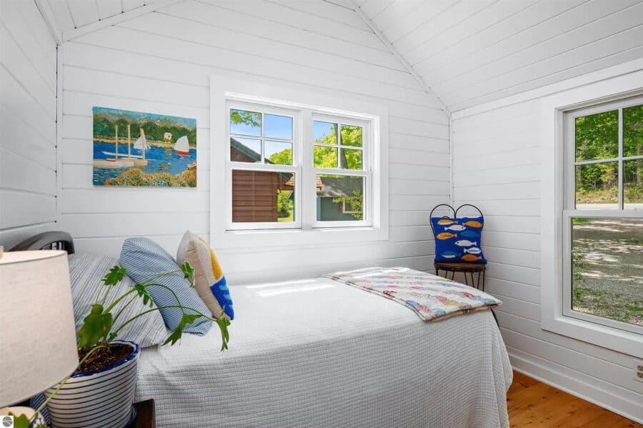 Cozy tiny house bedroom with white walls, large windows, and simple decor.