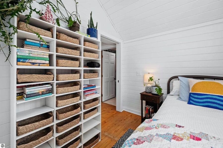 Charming bedroom inside a 635 sq. ft. Driftwood Cottage log cabin with white walls, wooden flooring,.
