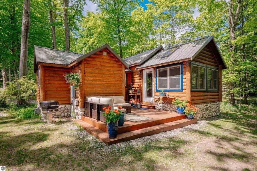 Cozy log cabin with porch in lush wooded area, perfect for small space living.