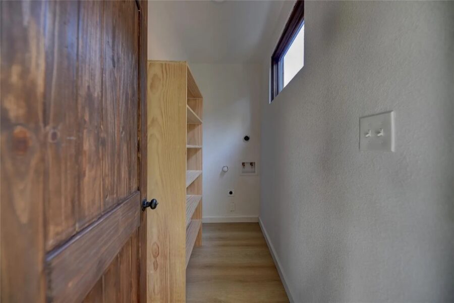 Compact tiny house interior with wooden shelves and natural light.