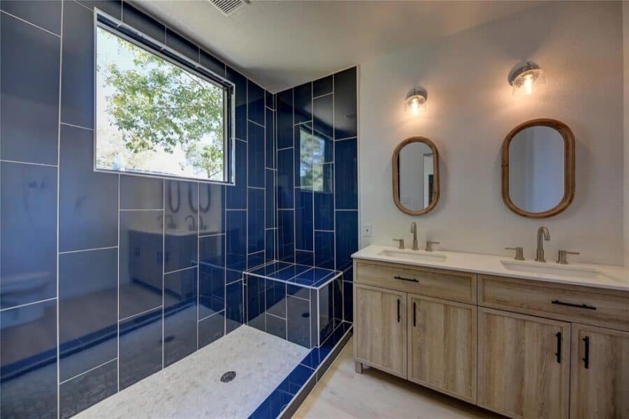 Bright bathroom featuring navy blue tiled walls and a spacious walk-in shower in a tiny home.