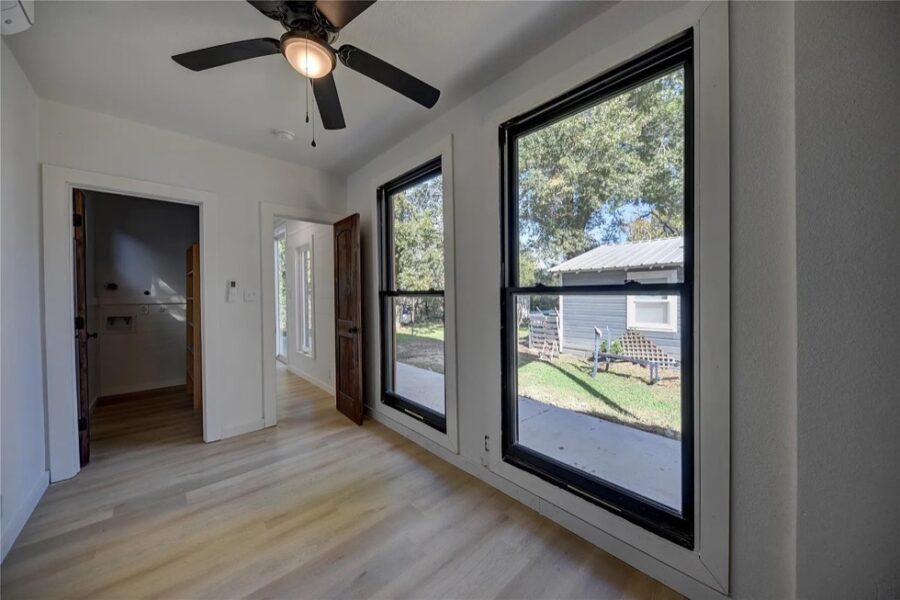 Bright interior with large windows and ceiling fan in a double unit shipping container home.