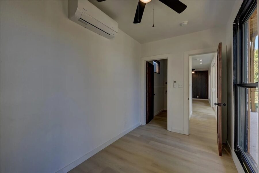 Interior of a modern tiny house with white walls, ceiling fan, and large window in Brenham, Texas.