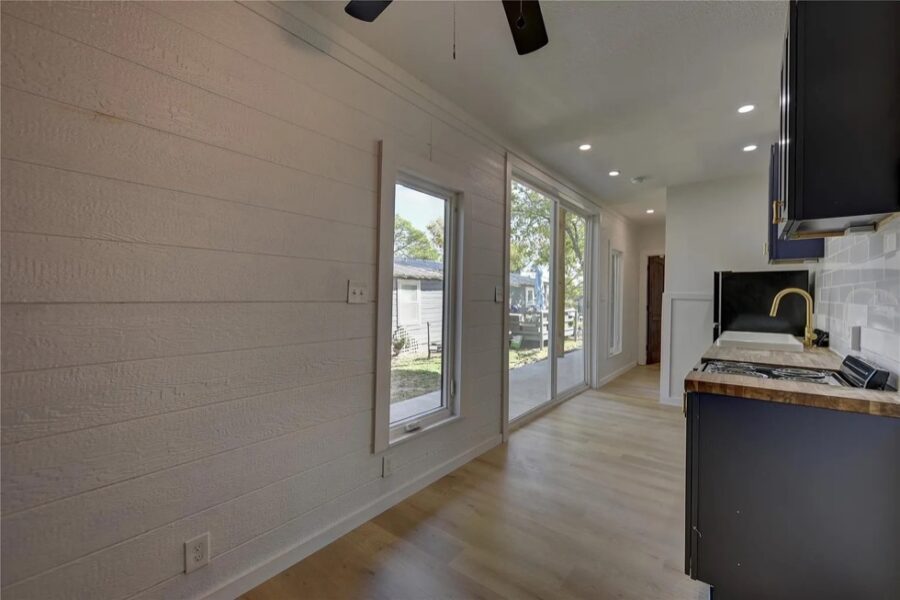 Bright tiny house interior with large windows, open living space, and modern kitchen design.