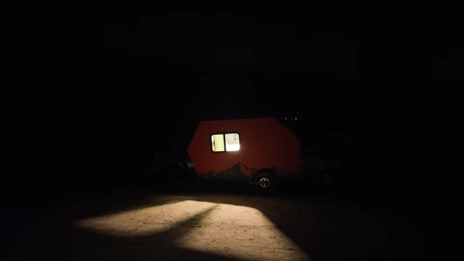 The orange camper glowing from its window at night