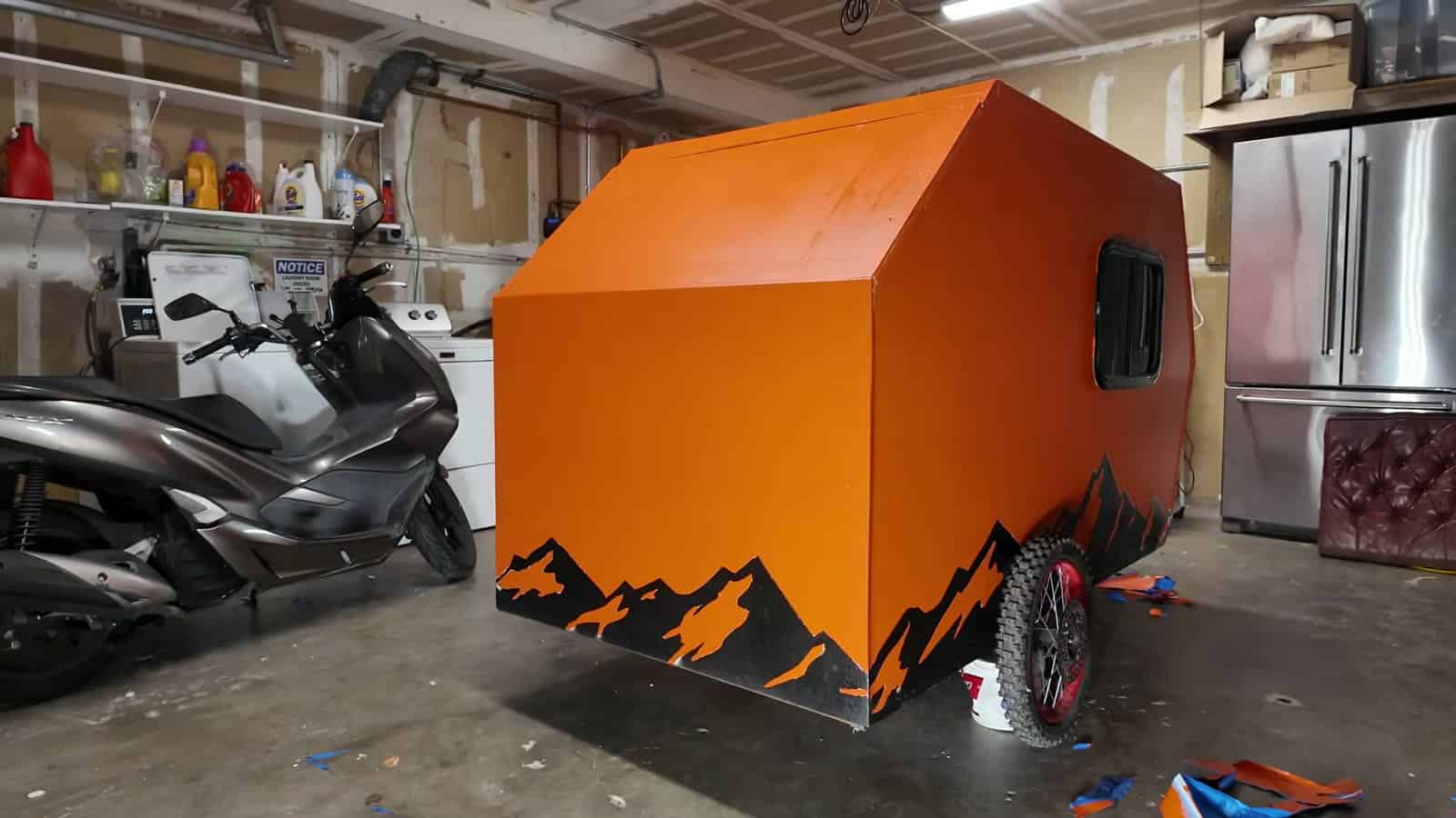 Freshly painted orange e-bike camper with black mountain graphics parked in a garage