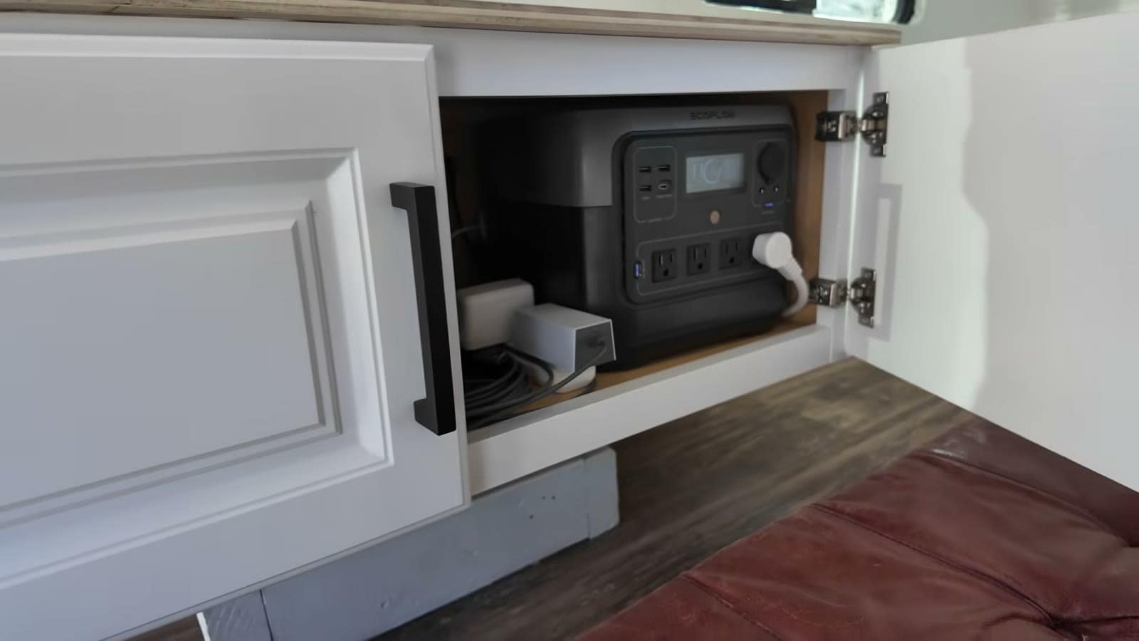 EcoFlow portable power station plugged in inside the camper's white cabinet