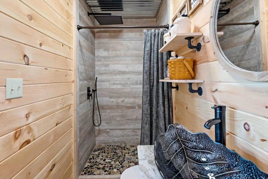 Small rustic bathroom with pebble shower floor and wooden walls in Eagles Nest Cabin, West Virginia.