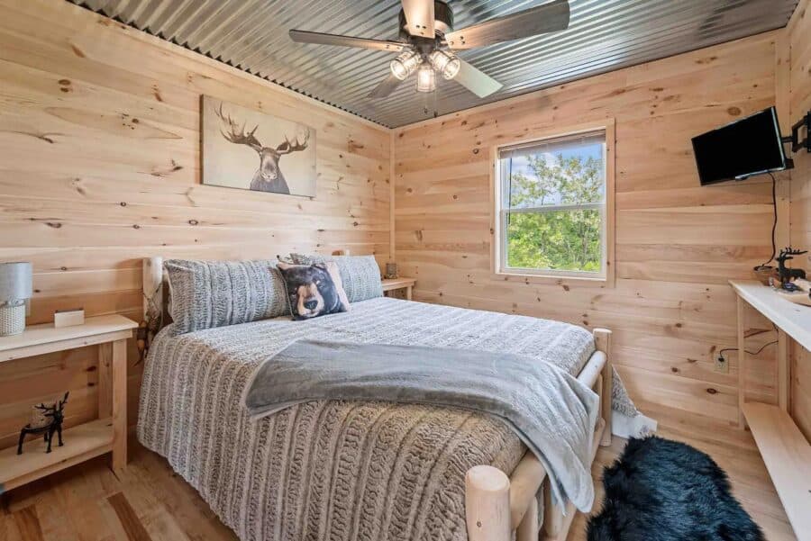 Charming rustic bedroom in Eagles Nest Cabin, West Virginia, with wood-paneled walls and natural lig.