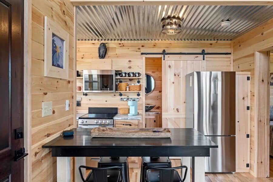 Compact tiny house kitchen with modern appliances and rustic wood accents.
