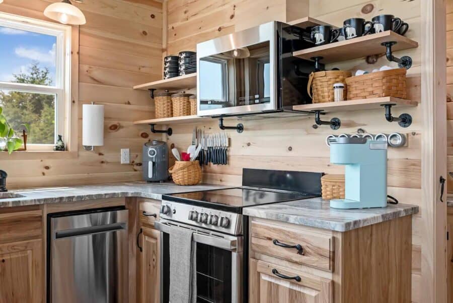 Bright tiny kitchen with wooden cabinets and open shelves in Eagles Nest Cabin, West Virginia.