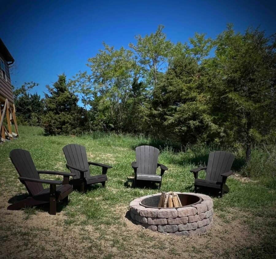 Outdoor fire pit with Adirondack chairs in a natural setting.