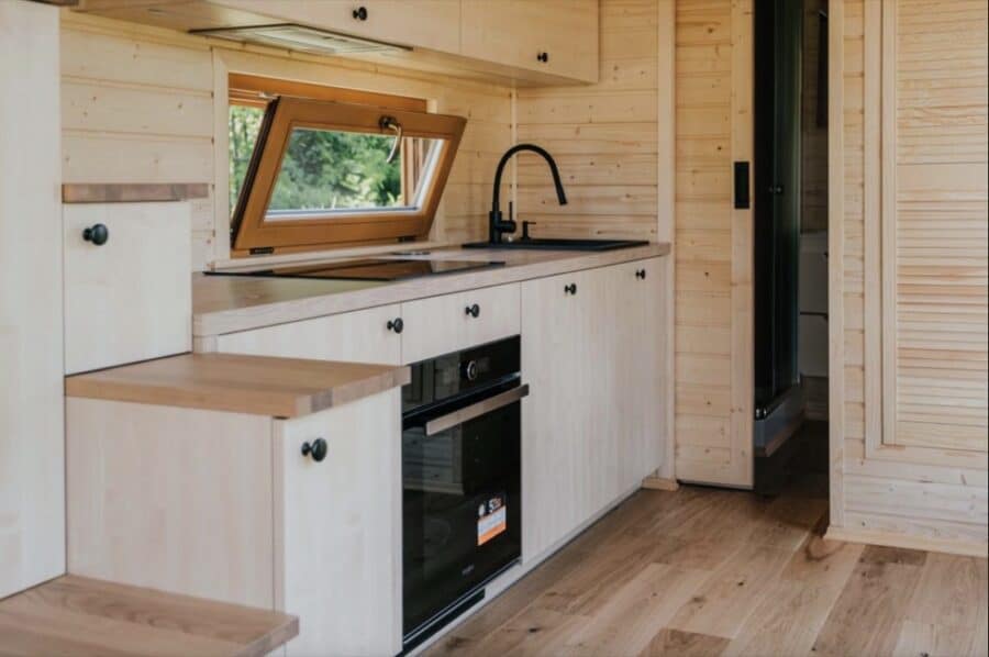 Cozy tiny house kitchen with natural wood finishes and modern appliances.