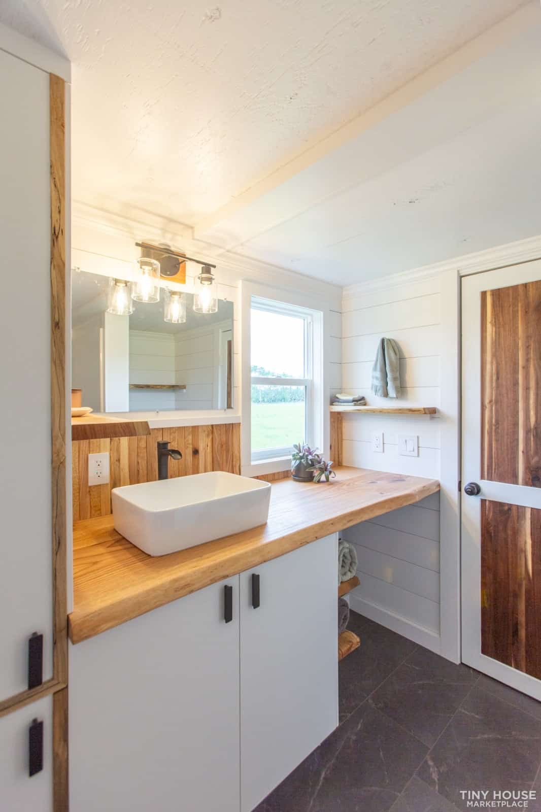 Elderberry bathroom with an oak counter, white vessel sink, LED vanity light, and a window