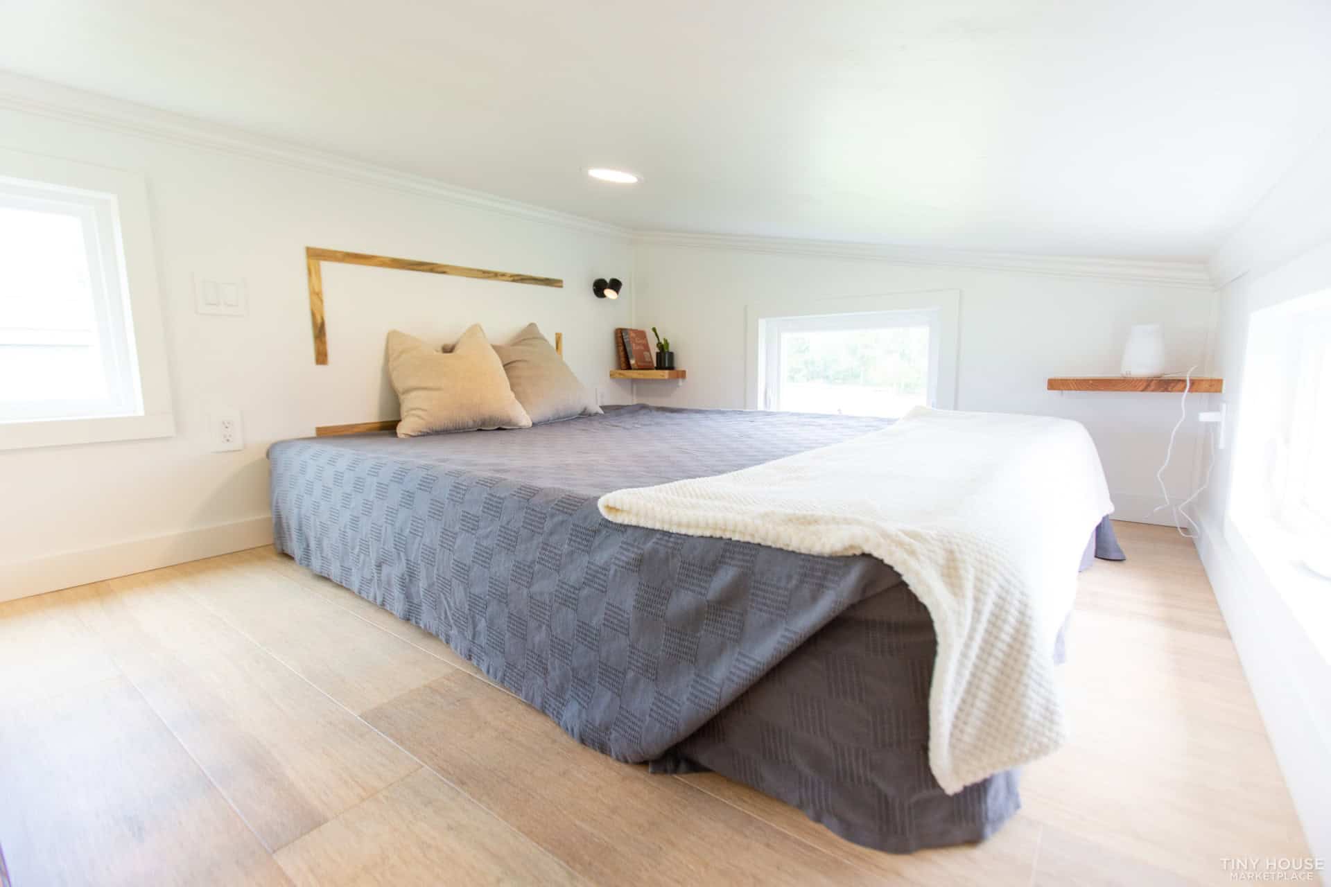 Queen bed in the Elderberry's 80-square-foot main loft with white walls, wood floors, and windows