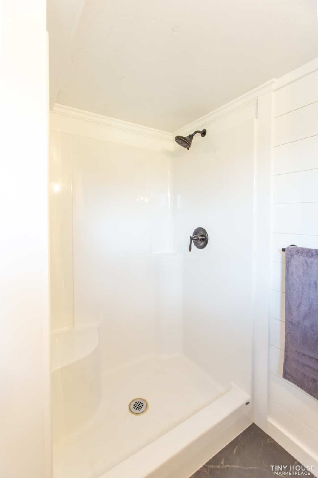 White 48 by 36 inch shower stall with a black shower head in the Elderberry bathroom