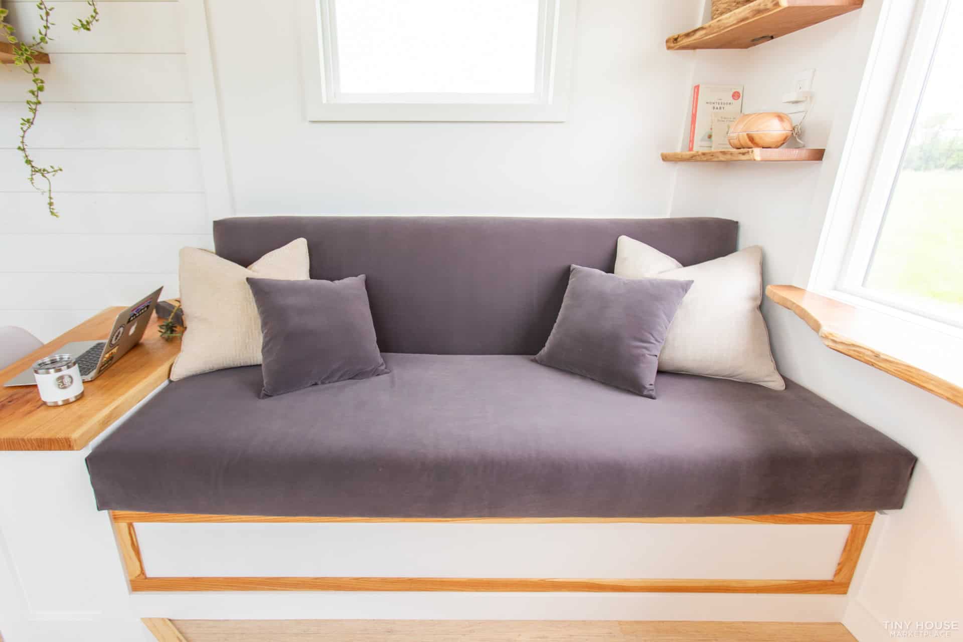 Custom gray velvet couch with elm trim and storage base in the Elderberry tiny house living room