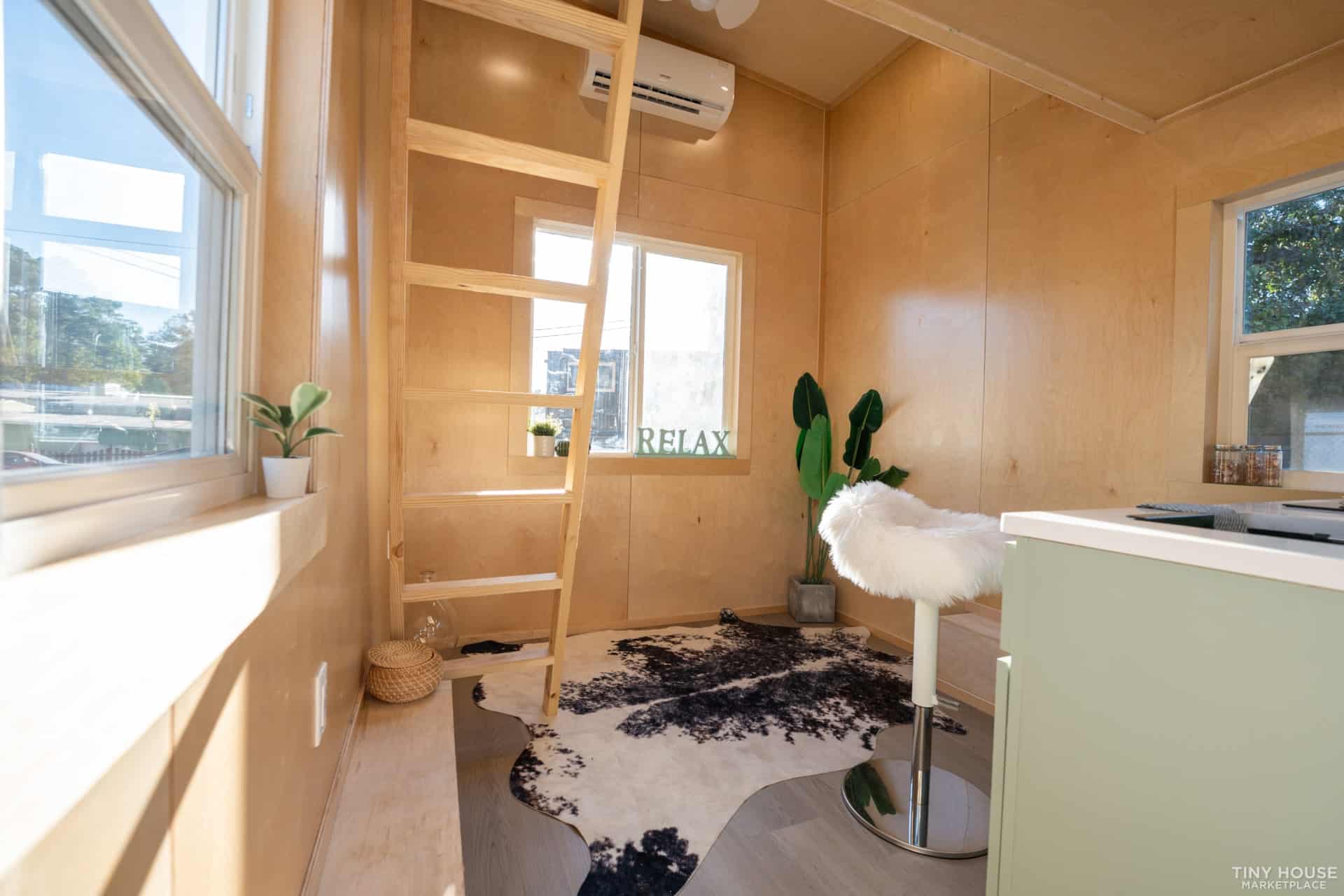 Interior of a tiny house featuring a ladder, cozy seating, and natural light. Compact, stylish, and.