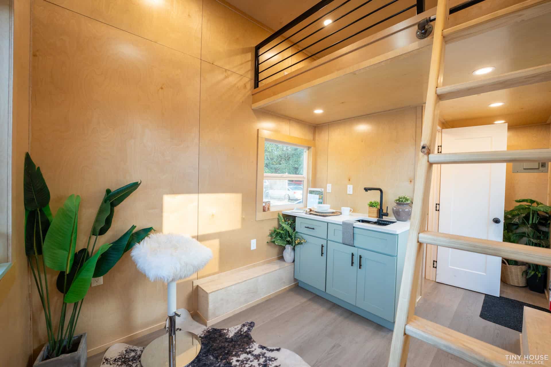 Small modern tiny house kitchen with loft and cozy interior design.