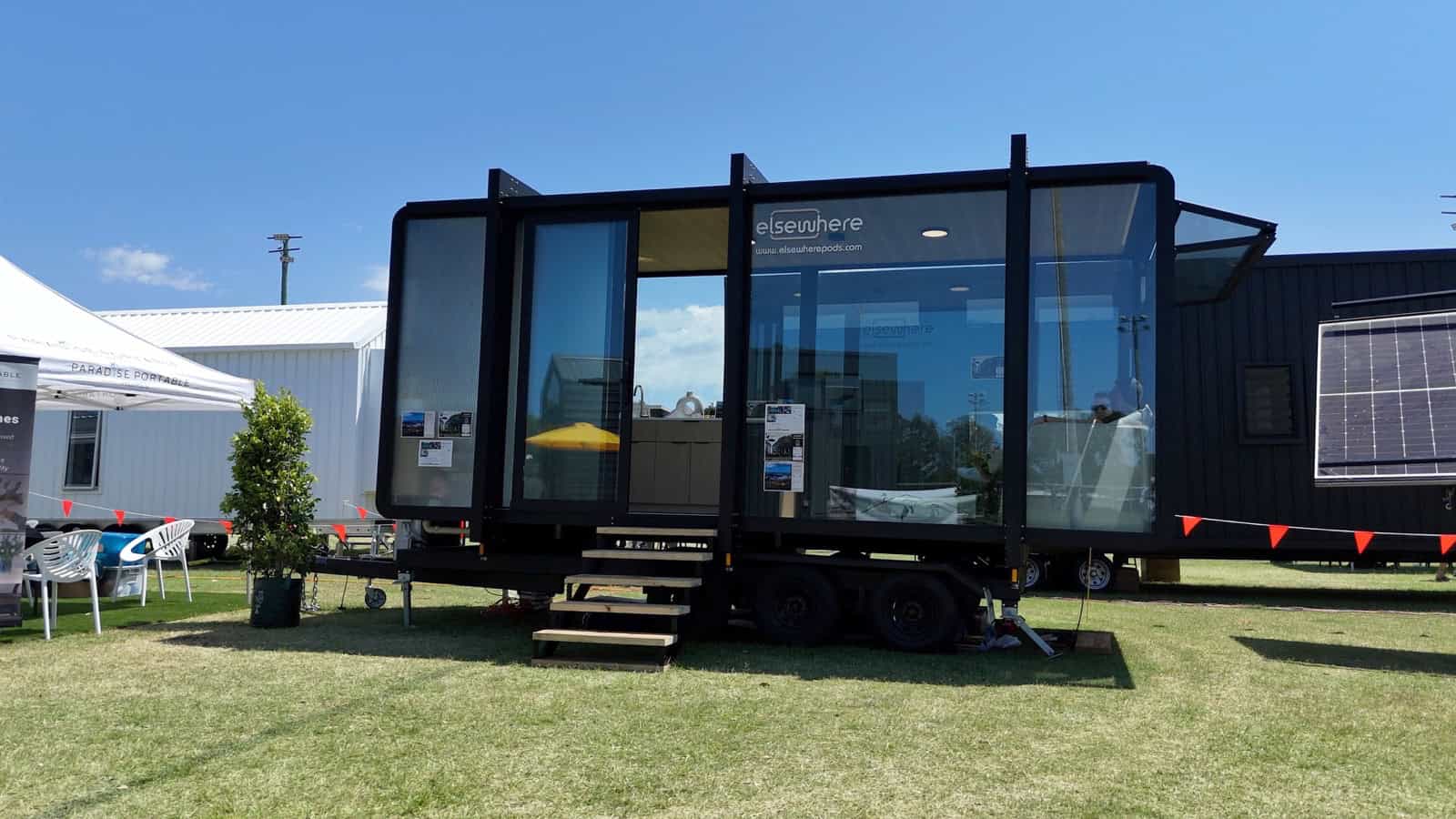 Side profile of the Elsewhere Pods 6m Tiny Home on Wheels showing tandem axles and timber entry stairs