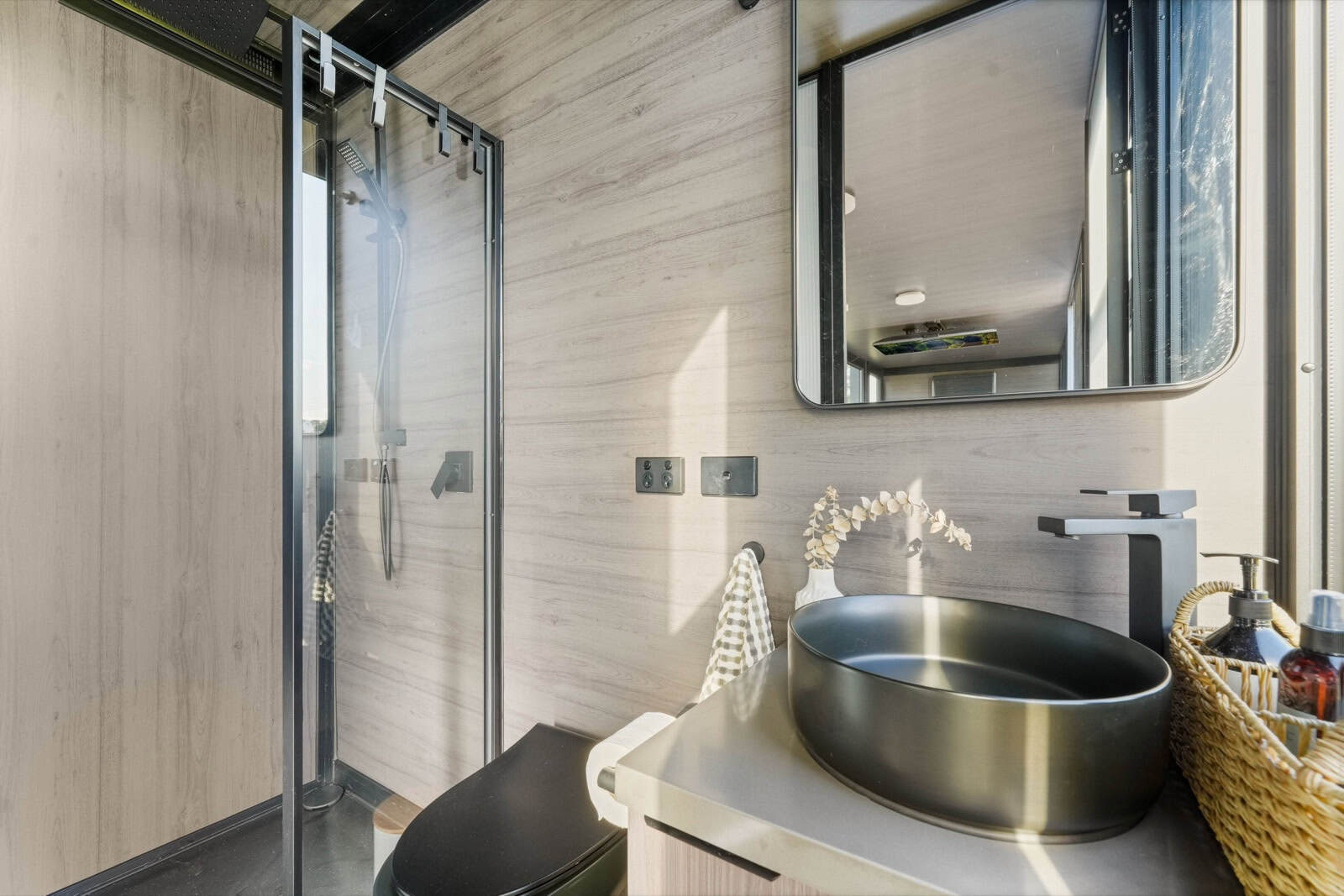 Bathroom of the Berry 8m pod with glass shower enclosure, black vessel basin, and composting toilet