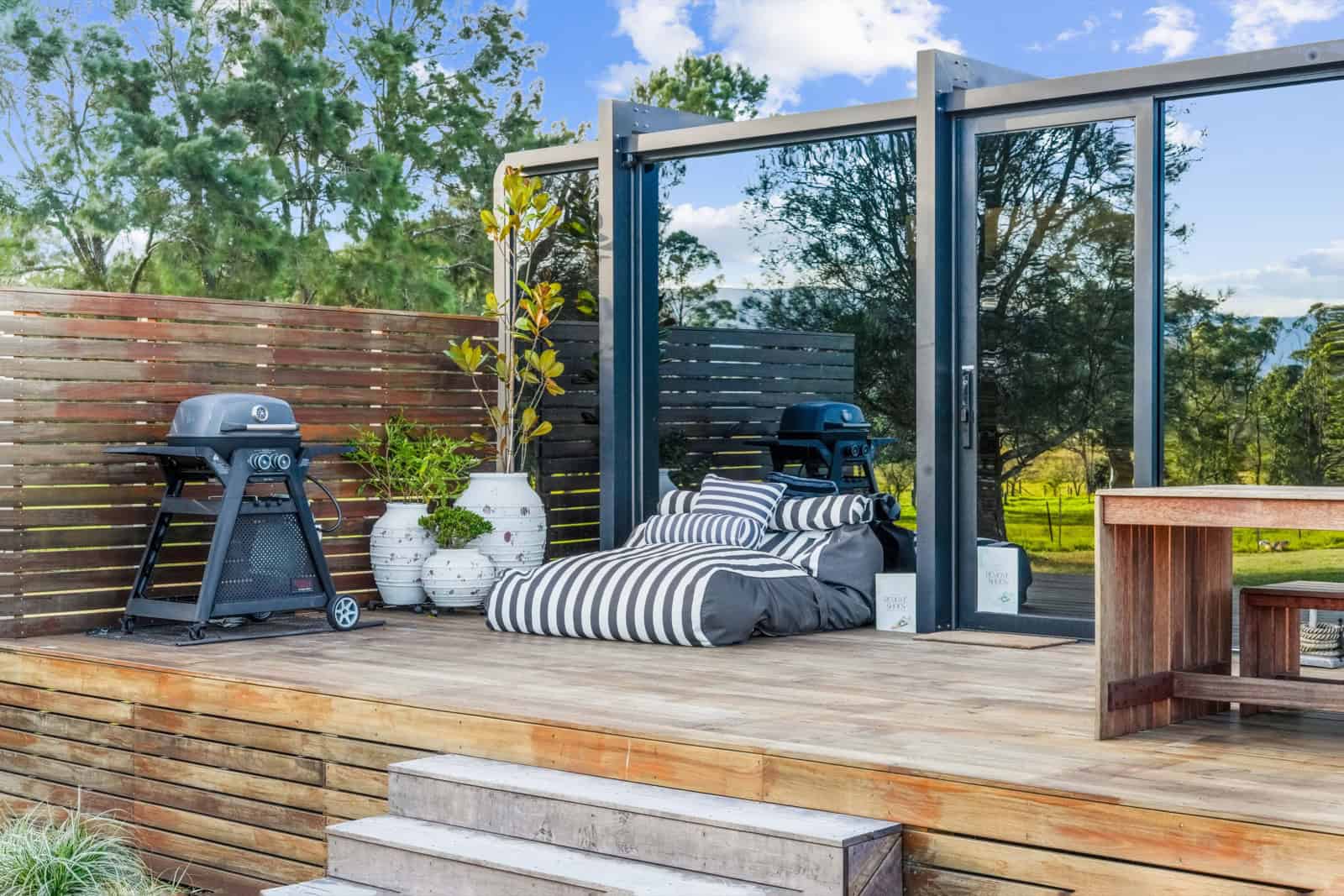 Timber deck with a slatted privacy screen concealing the barbecue, bean bags, and a hardwood table